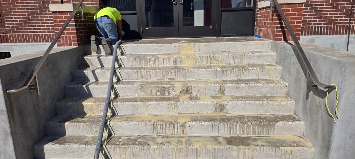 Stained and weathered concrete entry steps at a brick building before resurfacing