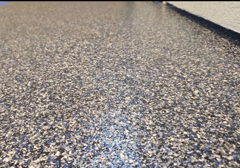 Close view of black and white flake coating meeting a light gray cove base