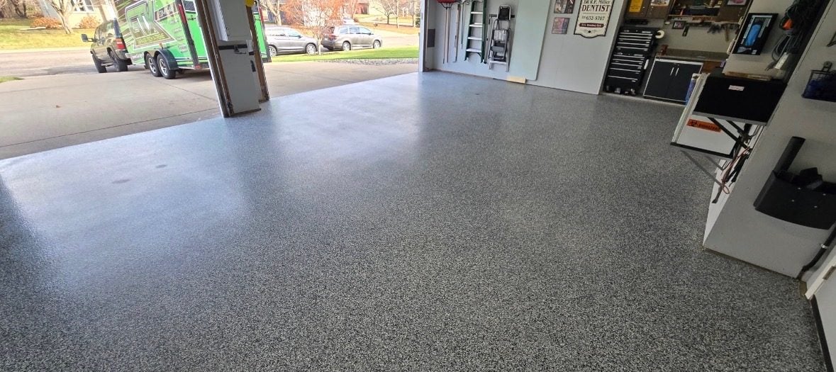 Gray and white flake garage floor with the door open, tool chest and driveway beyond