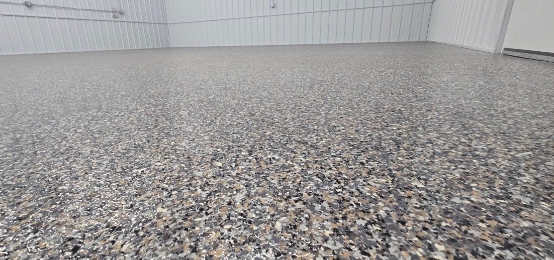 Gray, black and tan flake floor spanning a white steel-lined shop interior