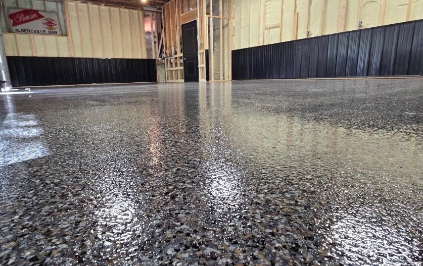 Brown, black and tan flake floor in a pole building with bar signage on the wall