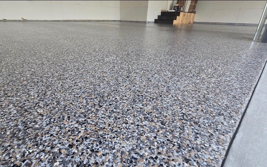 Black, tan and white flake floor sweeping toward interior steps and a service door