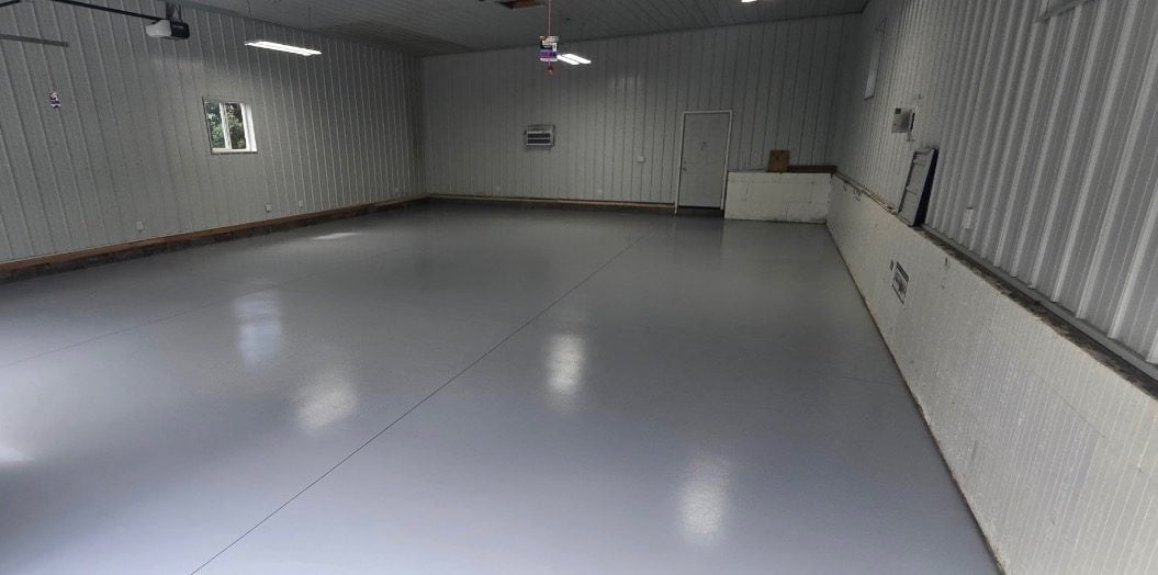 Solid light gray coating covering a large steel-sided pole building floor
