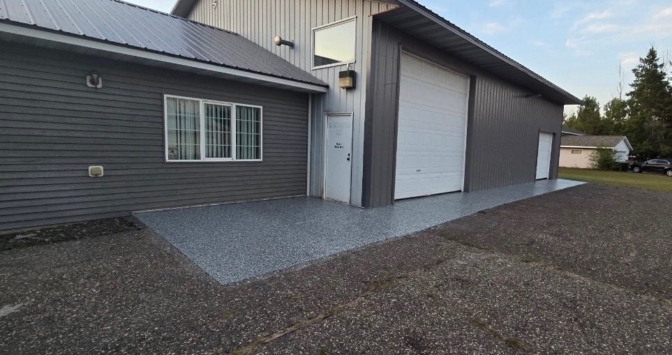 Gray flake coating on an exterior concrete apron running along a steel pole barn