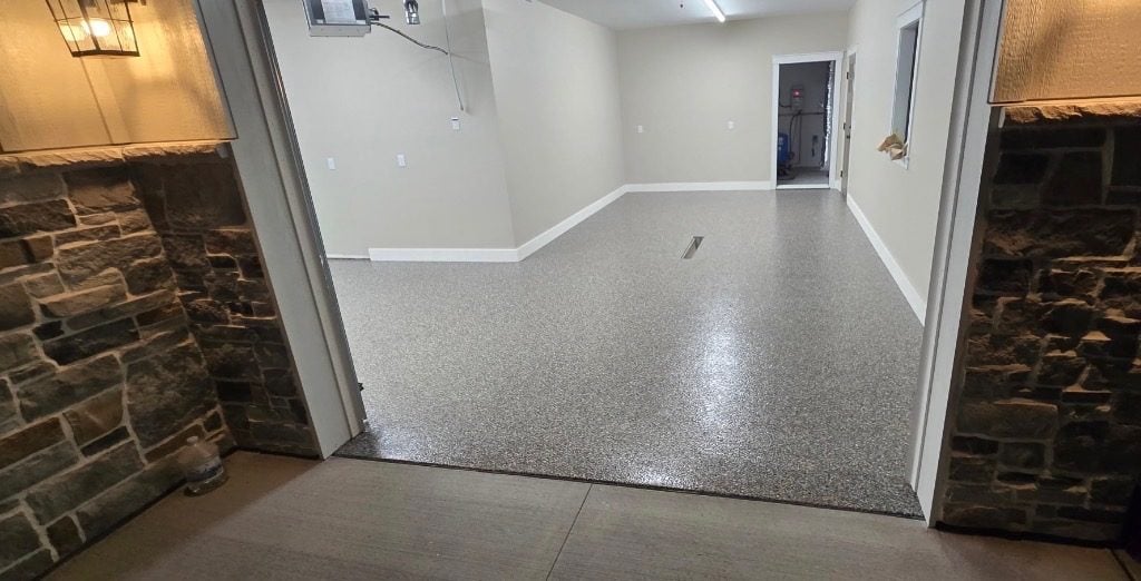 Gray and tan flake garage floor viewed from a stone-walled entry doorway