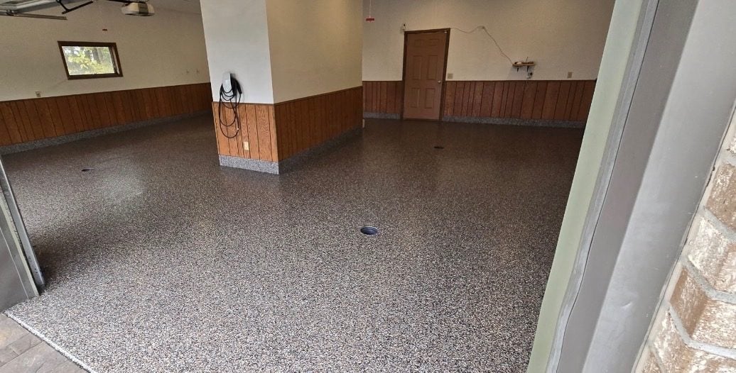 Brown and tan flake garage floor with wood wainscot walls and floor drains