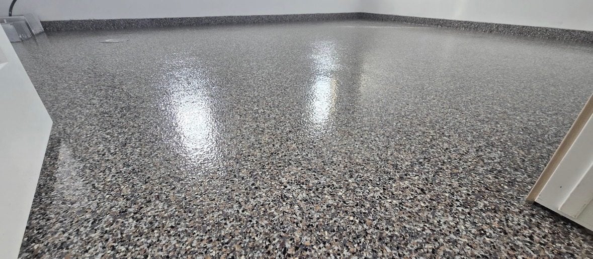 Glossy gray and brown flake floor curving into a white wall corner