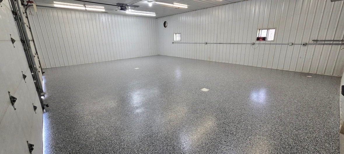 Gray, white and black flake floor filling a large white steel-lined garage