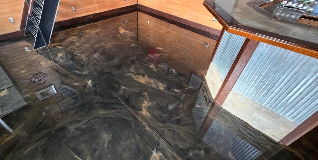 Bronze and charcoal metallic epoxy floor in a knotty-pine basement bar area