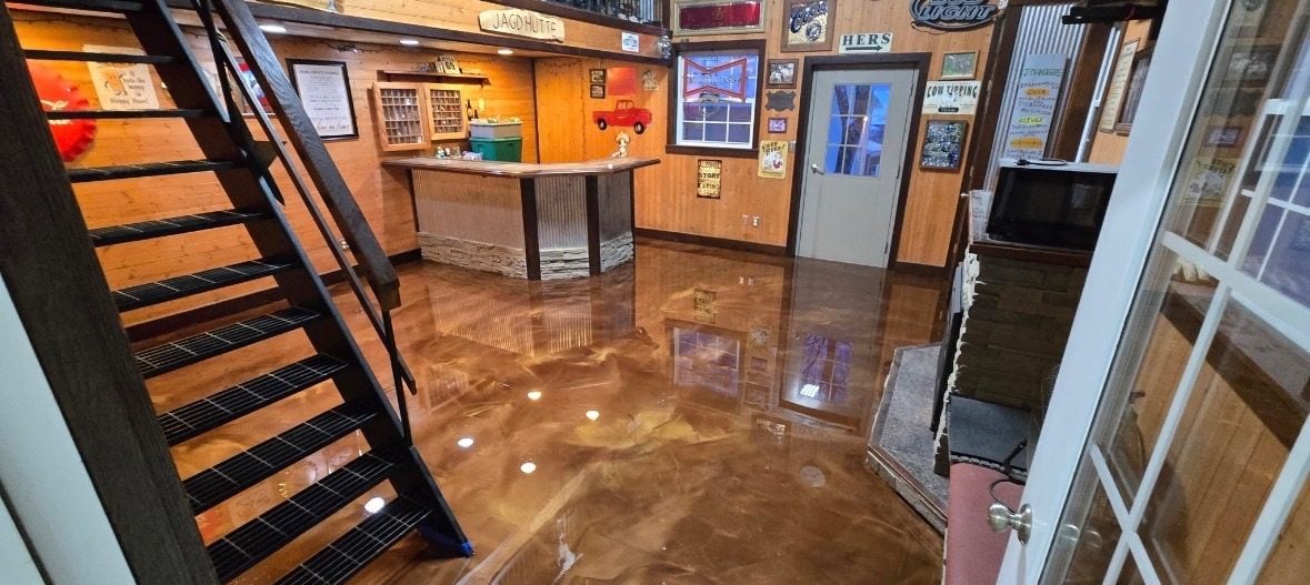 Copper metallic epoxy floor in a finished basement bar with open stairs