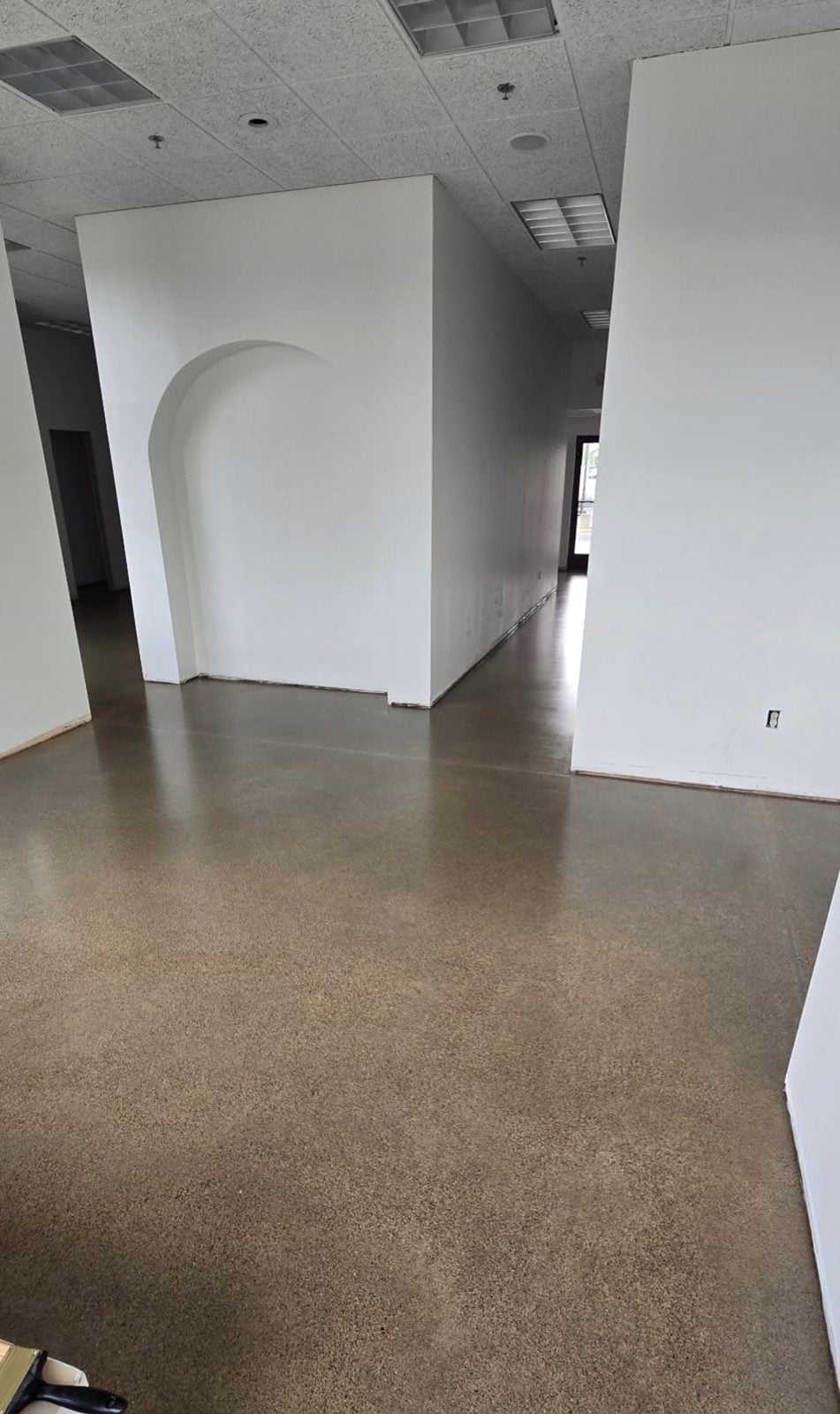 Solid tan-brown coated floor in a vacant retail space with white partition walls