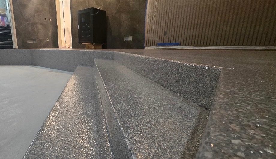 Charcoal flake coating wrapping interior steps and landing beside a smooth gray floor
